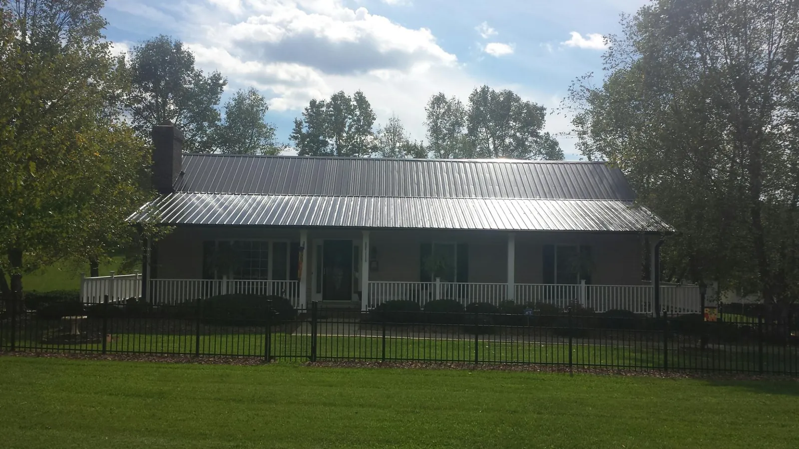 Gray metal roof on a brick ranch with a full width front porch — Gutter Guard Installation work by our crew in Quitman