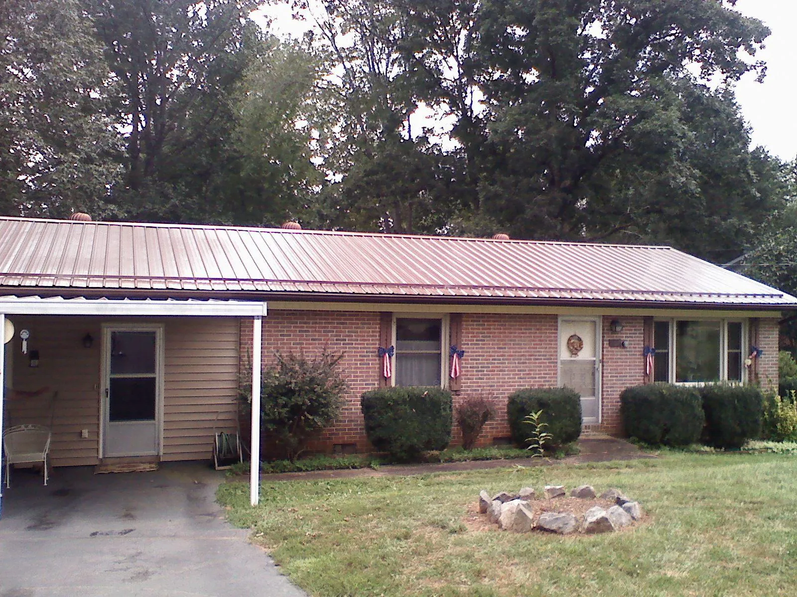Bronze metal roof and carport on a brick ranch home — Roof Repair work by our crew in Quitman