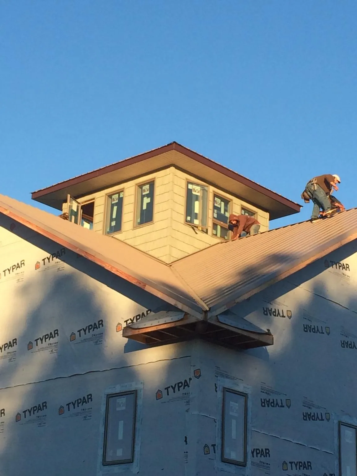 Roofers working around a rooftop cupola on a new metal roof at sunset — Roof Waterproofing in Quitman by Roofing Brothers